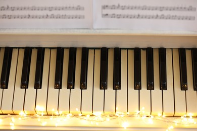 Glowing fairy lights on piano keys, above view. Christmas music