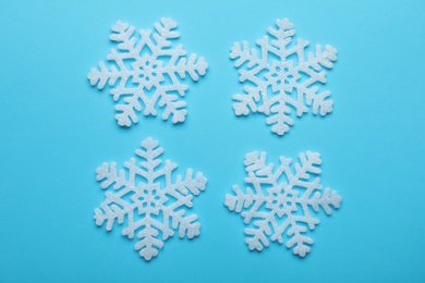 Beautiful decorative snowflakes on light blue background, flat lay