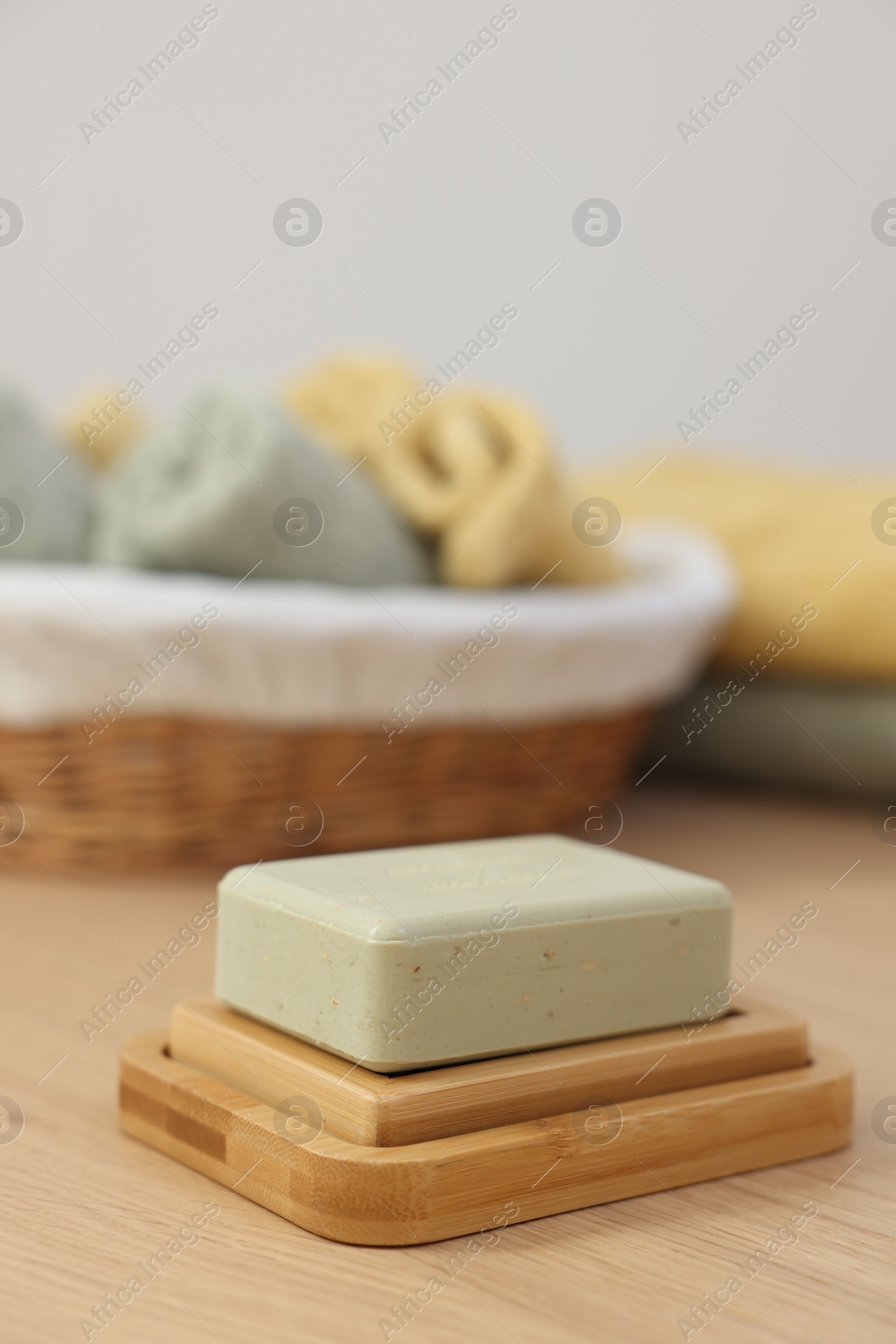 Photo of Soap bar and sponge on light wooden table, space for text. Spa therapy