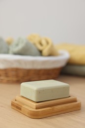 Soap bar and sponge on light wooden table, space for text. Spa therapy