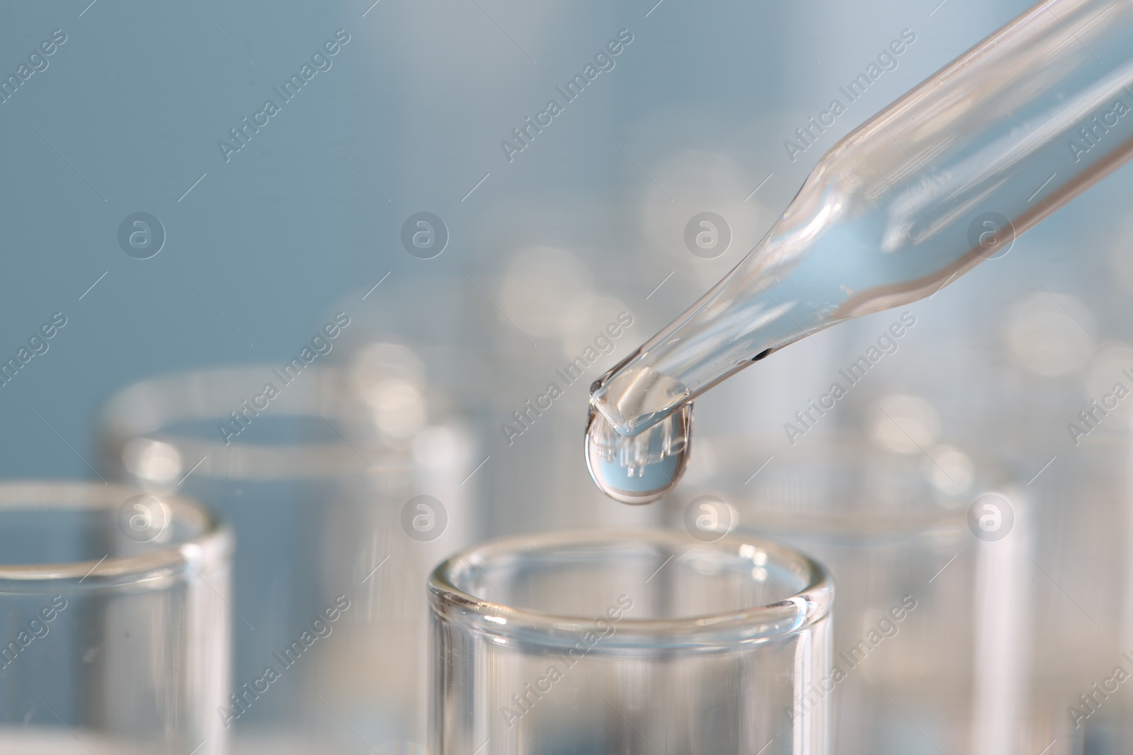 Photo of Laboratory analysis. Dripping liquid from pipette into glass test tube on blurred background, closeup. Space for text