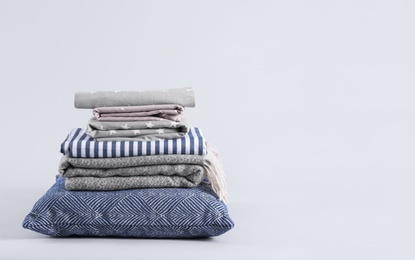 Stack of clean bed sheets and pillow on white background