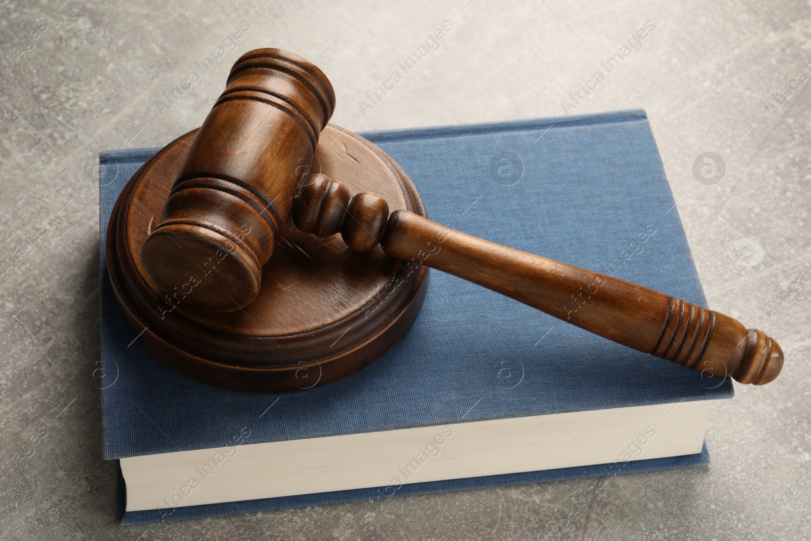 Photo of Wooden gavel, sound block and book on grey textured table, closeup