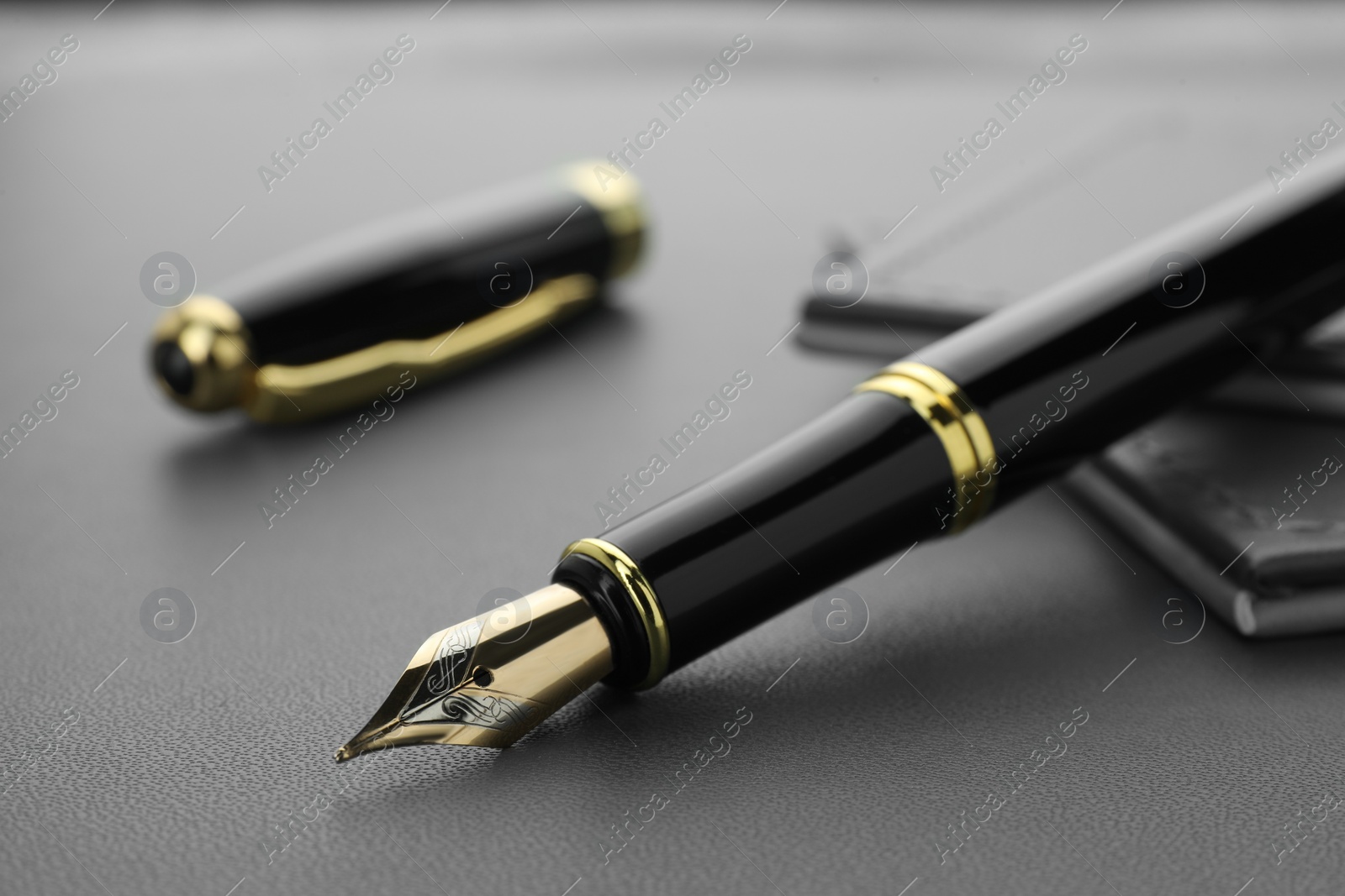 Photo of Stylish black fountain pen on grey textured table, closeup