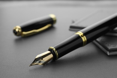 Stylish black fountain pen on grey textured table, closeup