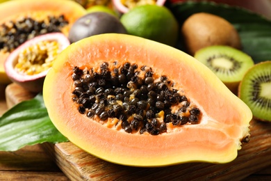 Fresh ripe papaya and other fruits on wooden table, closeup