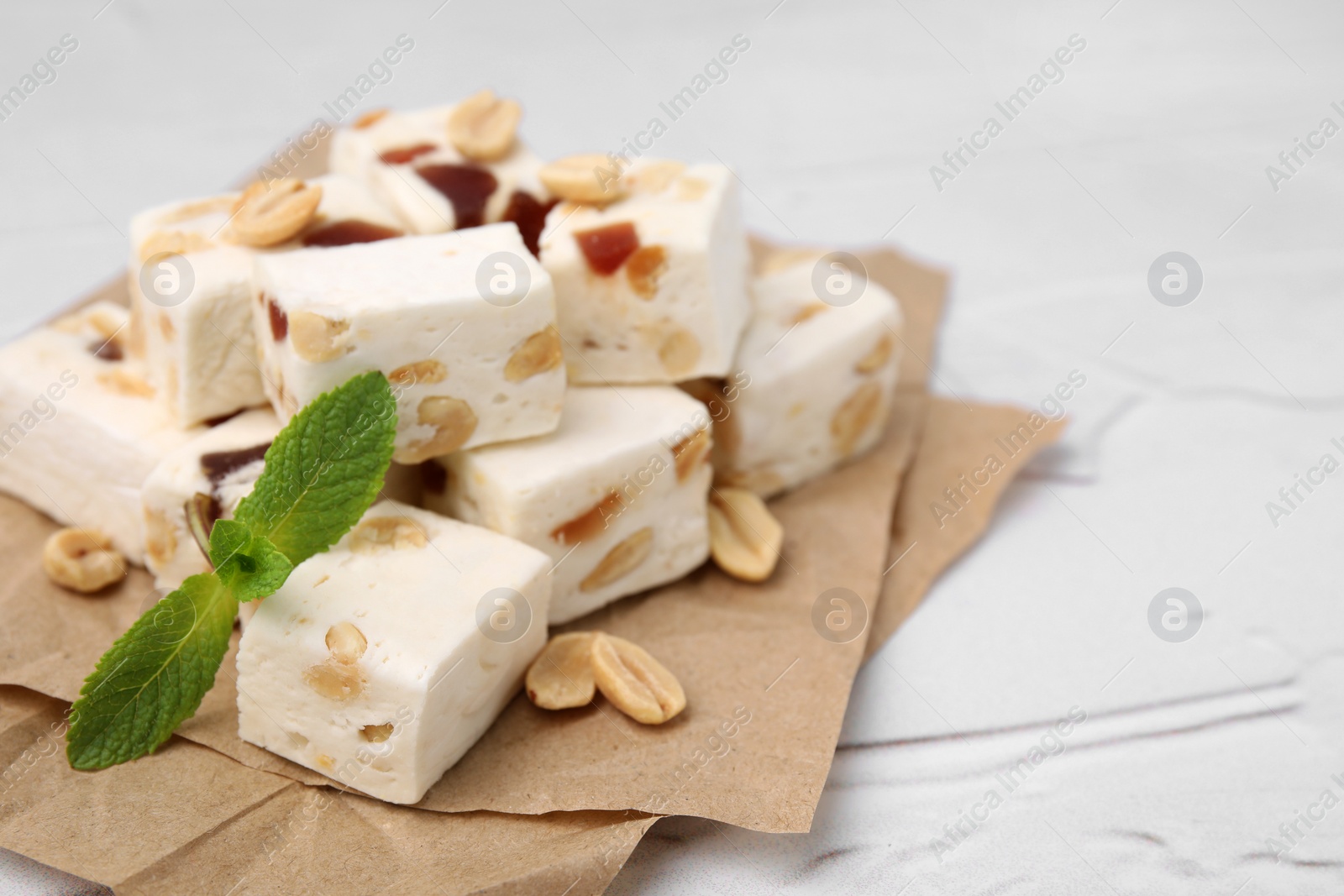 Photo of Pieces of delicious nutty nougat on parchment paper, closeup