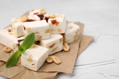 Photo of Pieces of delicious nutty nougat on parchment paper, closeup