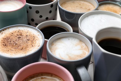 Many different cups with aromatic hot coffee on table, closeup