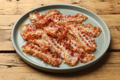 Delicious fried bacon slices on wooden table