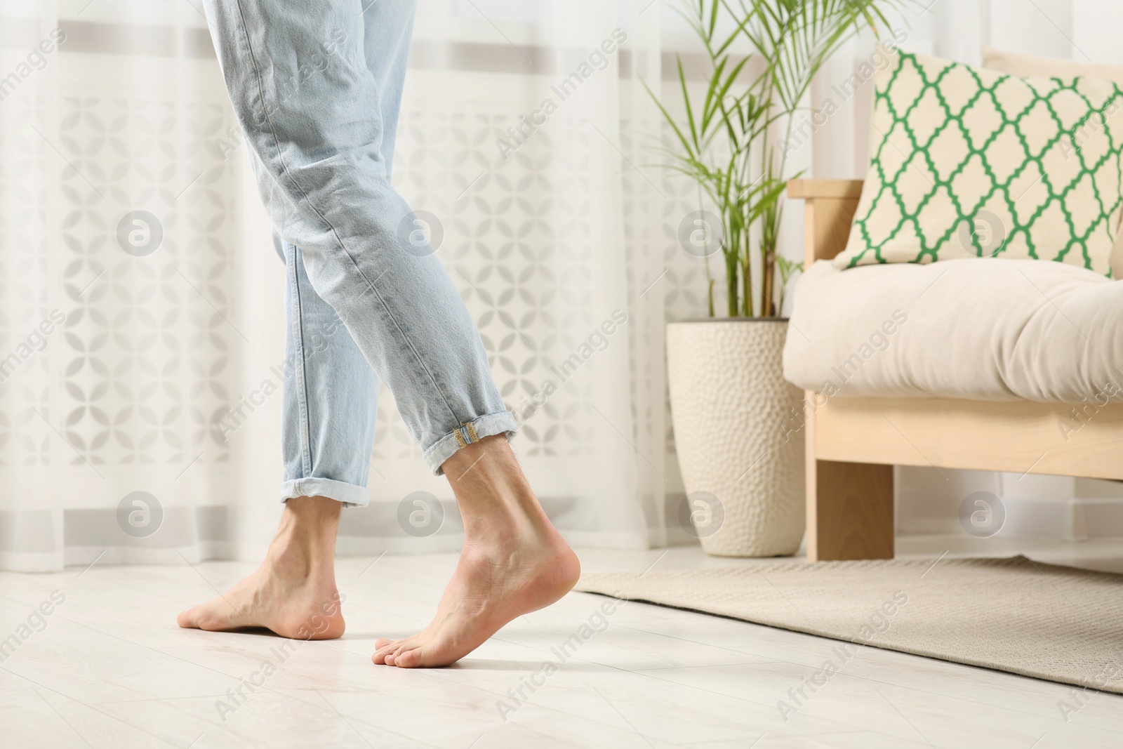 Photo of Barefoot woman walking on white parquet at home, closeup. Heated floor