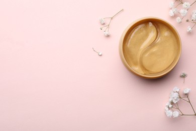 Photo of Under eye patches in jar and flowers on light pink background, flat lay. Space for text