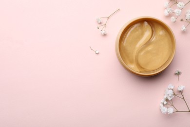 Under eye patches in jar and flowers on light pink background, flat lay. Space for text