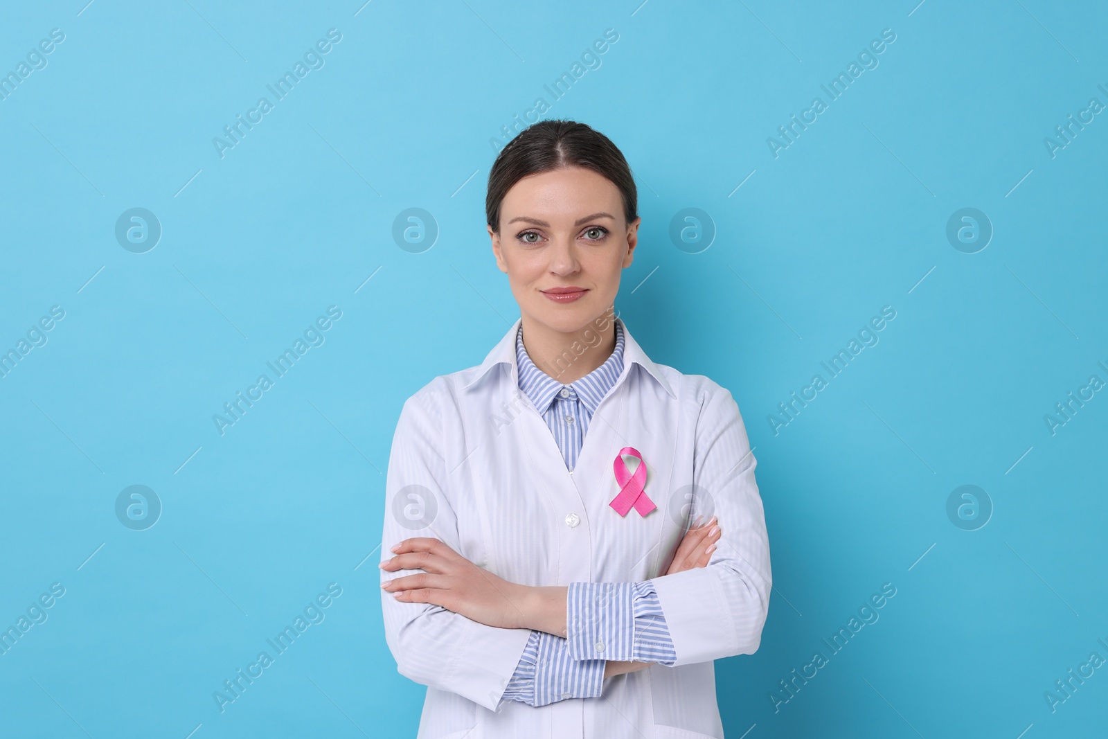 Photo of Mammologist with pink ribbon on light blue background. Breast cancer awareness