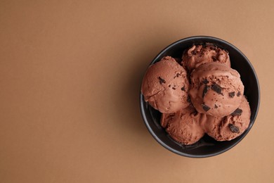 Photo of Bowl with tasty chocolate ice cream on light brown background, top view. Space for text