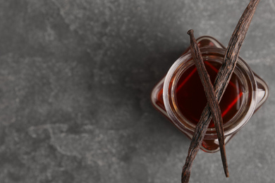 Photo of Aromatic homemade vanilla extract on grey table, top view. Space for text