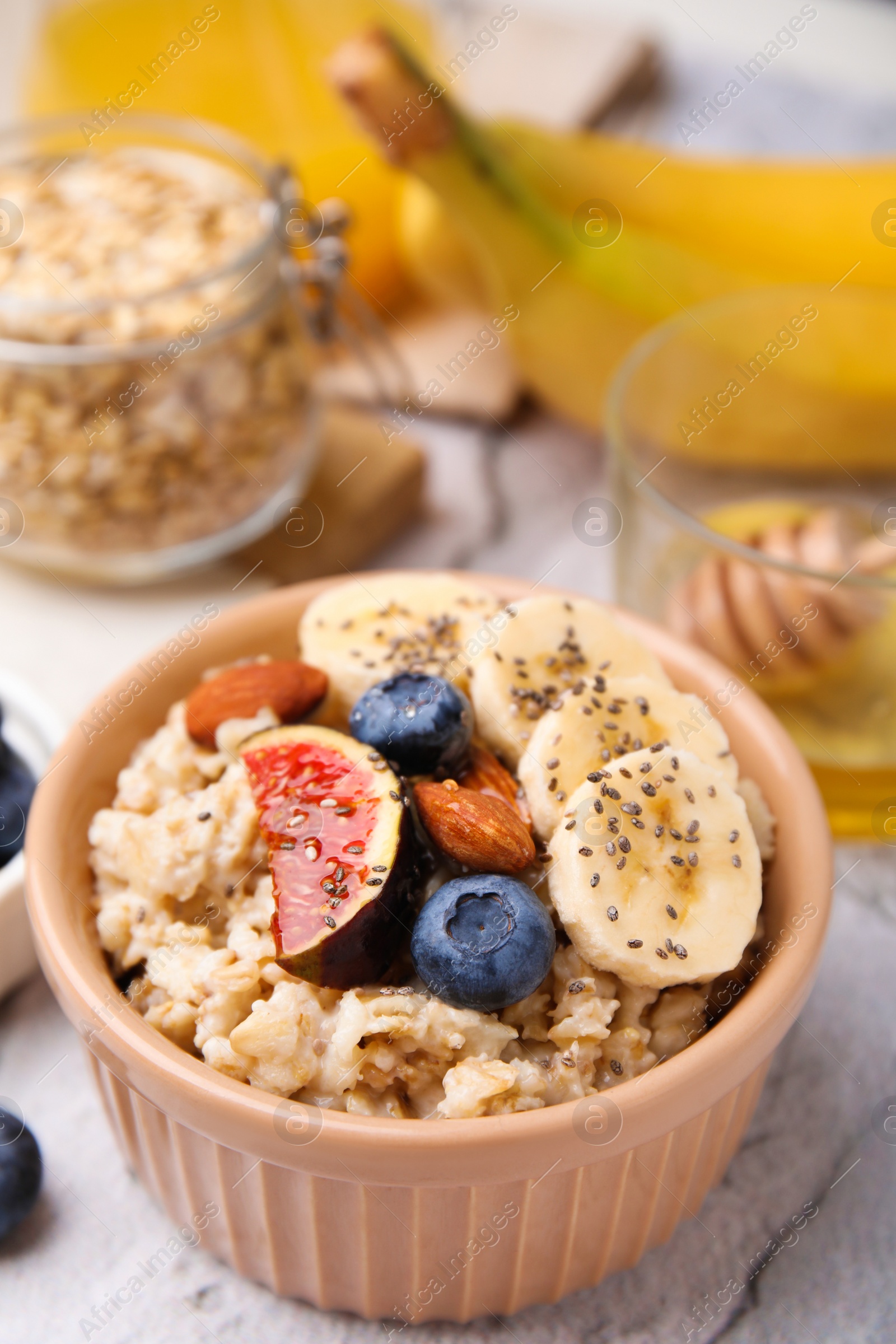 Photo of Bowl of oatmeal with blueberries, almonds, banana and fig pieces on white table