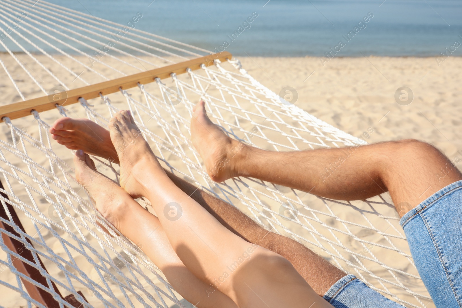 Photo of Young couple relaxing in hammock on beach, closeup