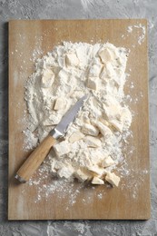 Making shortcrust pastry. Flour, butter, knife and wooden board on grey table, top view