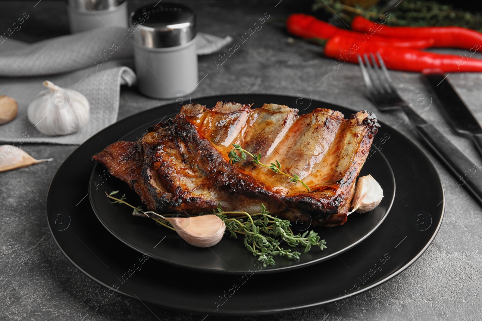 Photo of Tasty grilled ribs with thyme on grey table