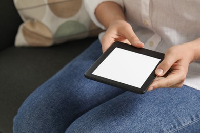 Photo of Young woman using e-book reader on sofa, closeup. Space for text