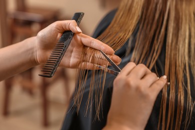 Professional hairdresser cutting girl's hair in beauty salon, closeup