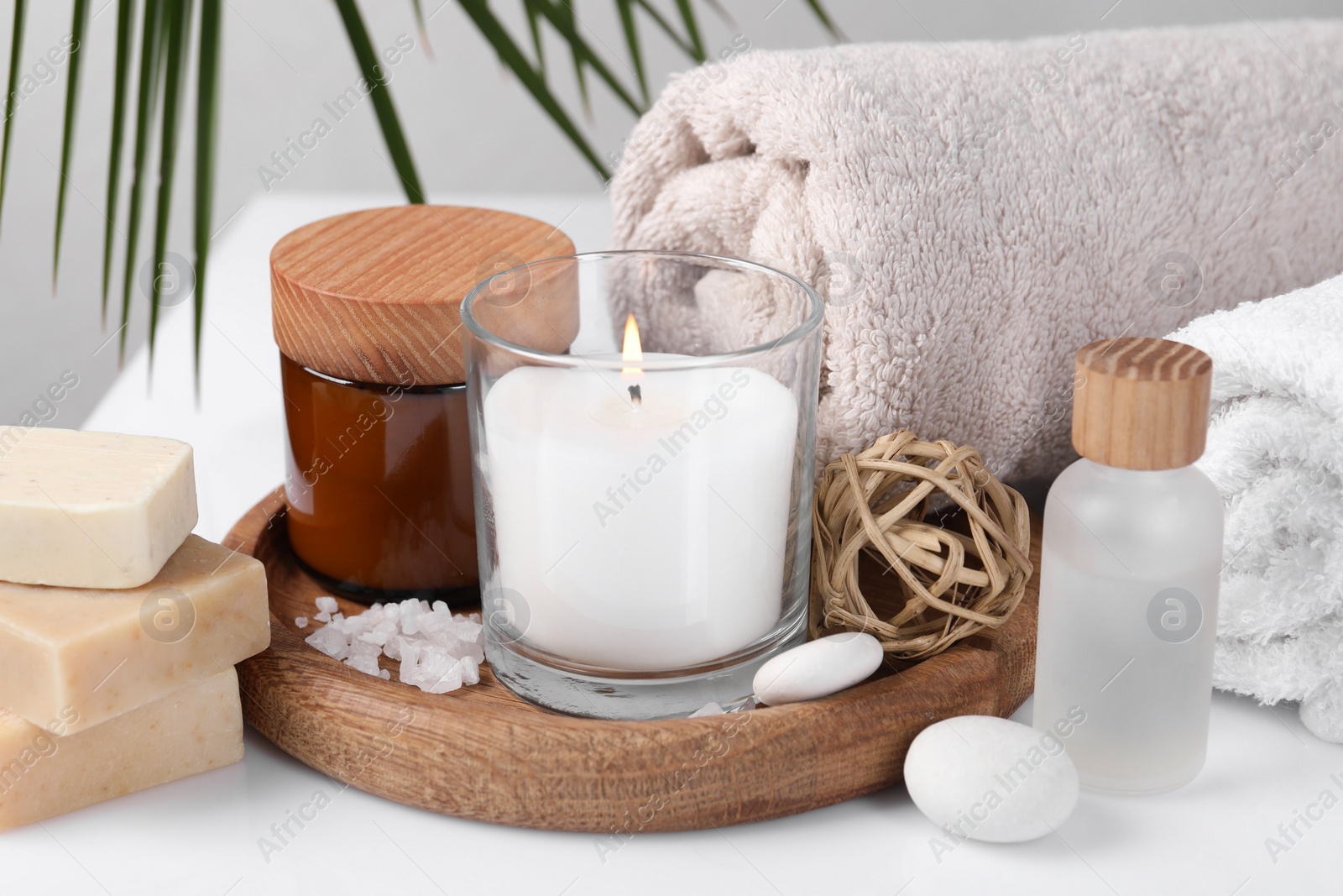 Photo of Composition with spa supplies on white table and palm leaf