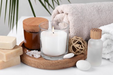 Composition with spa supplies on white table and palm leaf