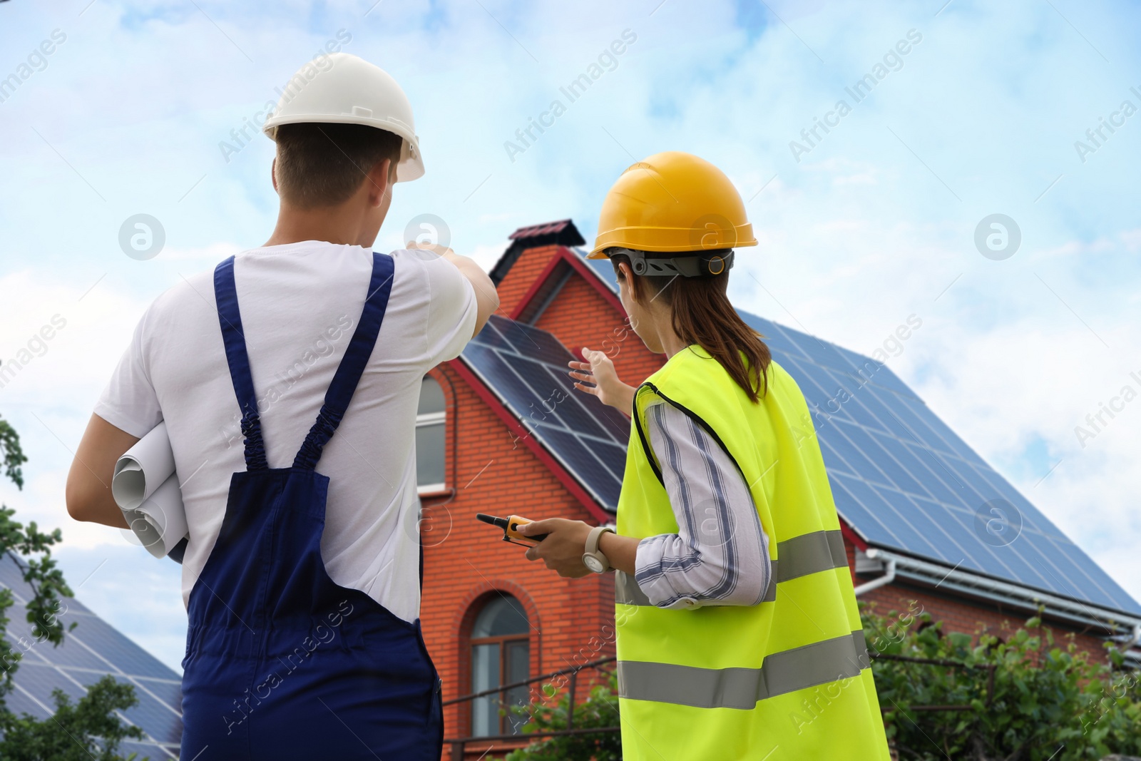 Image of Engineers near house with solar panels. Alternative energy source