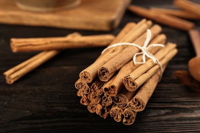 Aromatic cinnamon sticks on black wooden table, closeup. Space for text