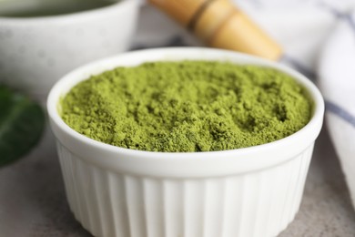 Photo of Green matcha powder on light grey table, closeup
