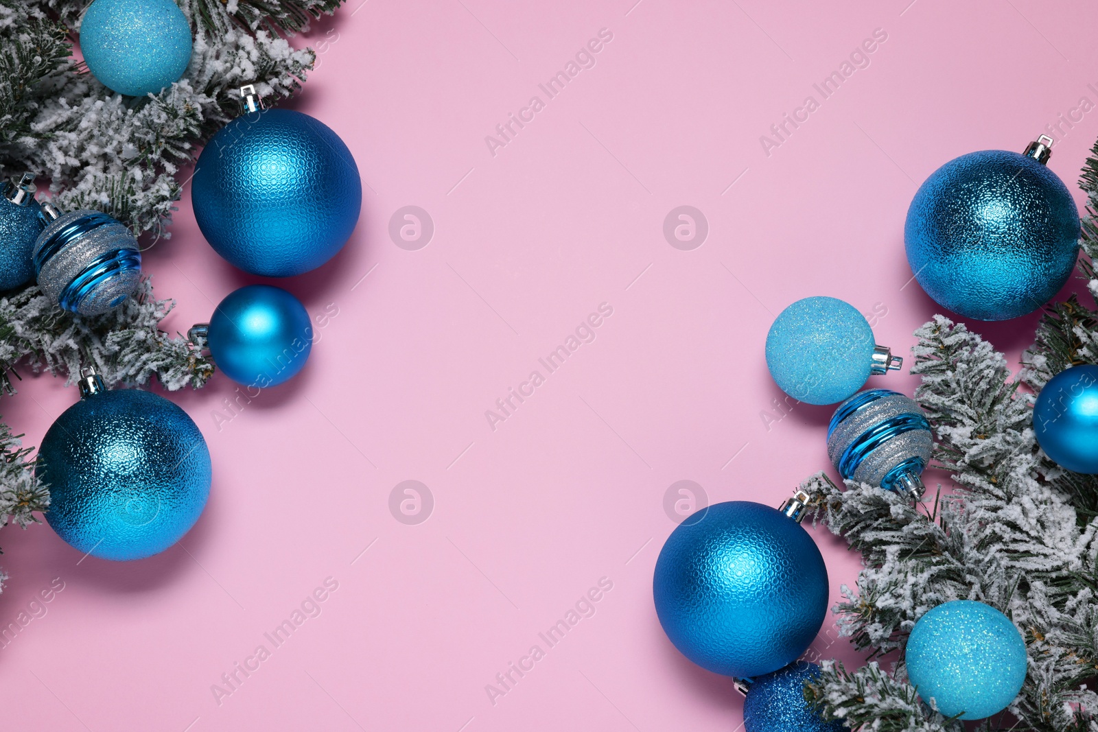 Photo of Shiny blue Christmas balls and fir tree branches with snow on pink background, flat lay. Space for text