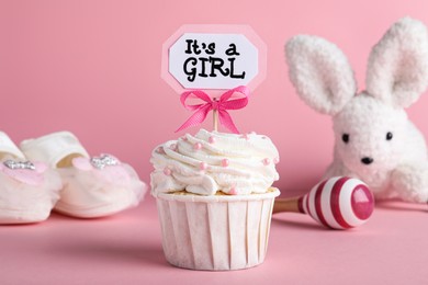 Beautifully decorated baby shower cupcake for girl with cream and topper on pink background