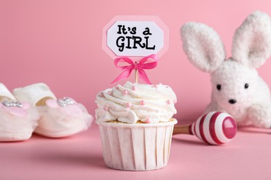 Photo of Beautifully decorated baby shower cupcake for girl with cream and topper on pink background