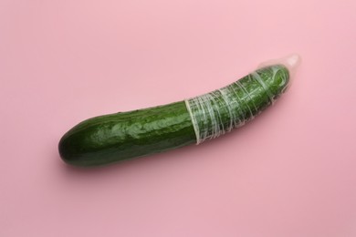 Photo of Cucumber with condom on pink background, top view. Safe sex concept
