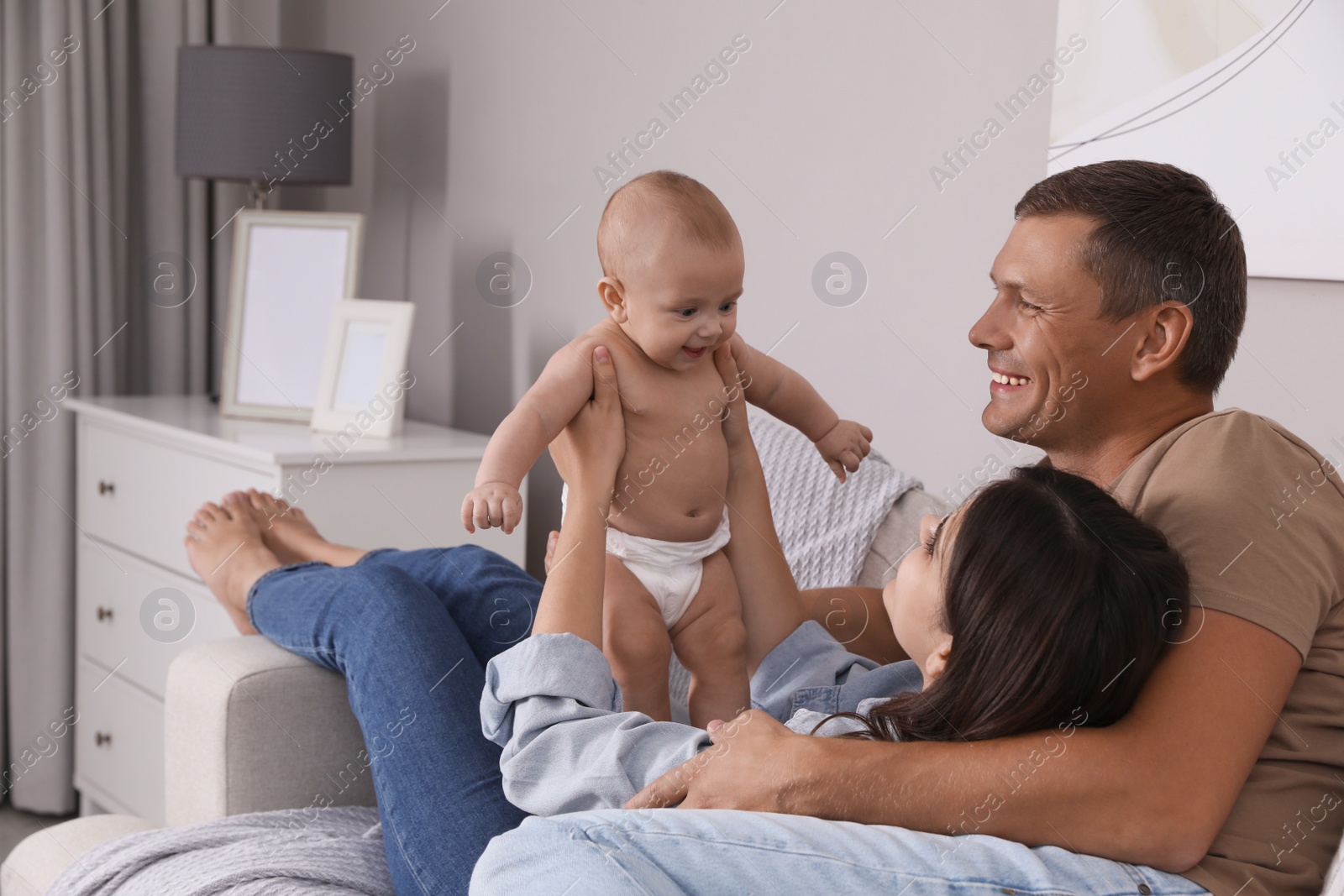 Photo of Happy family with their cute baby on sofa in living room