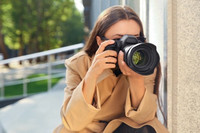 Private detective with camera spying near building on city street