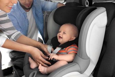 Photo of Mother fastening baby to child safety seat inside of car