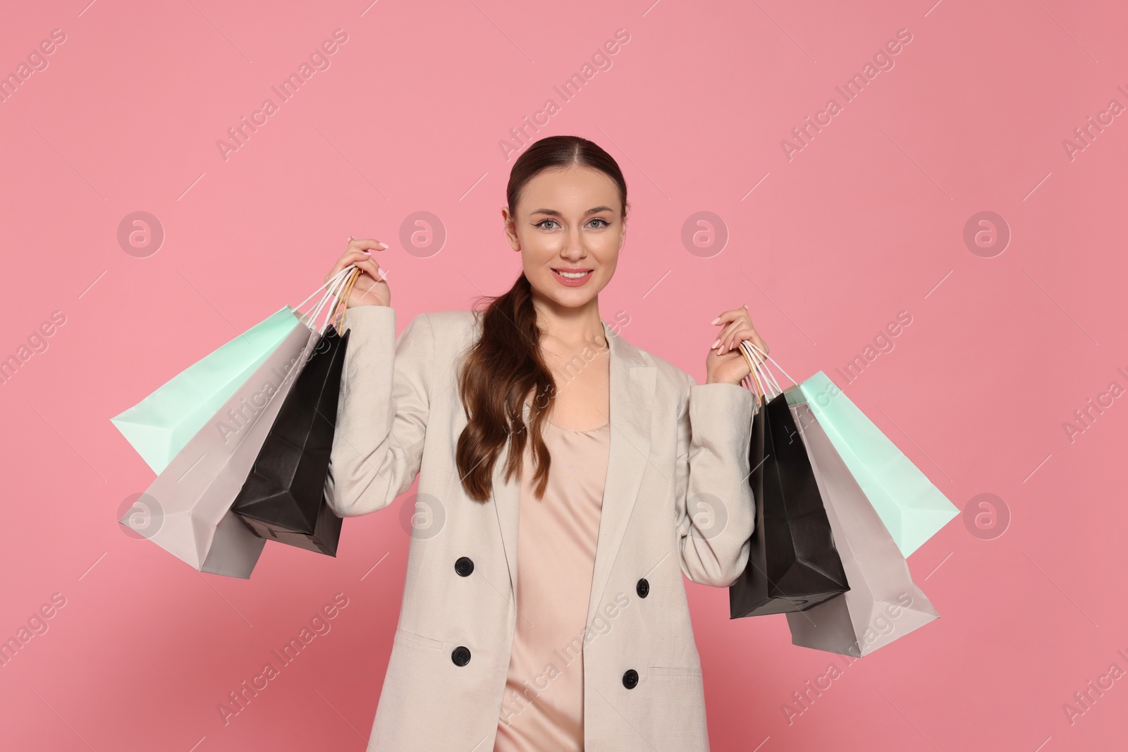 Photo of Stylish young woman with shopping bags on pink background