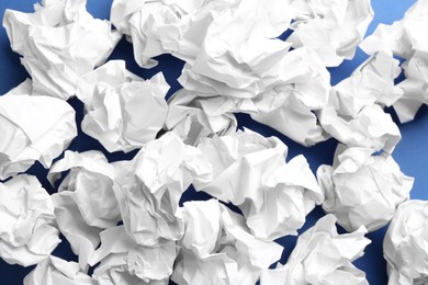 Photo of Crumpled sheets of paper on blue background, closeup