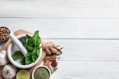 Flat lay composition with different natural spices and herbs on white wooden table, space for text