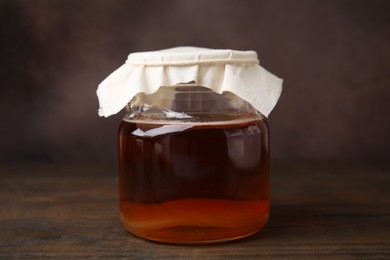 Tasty kombucha in glass jar on wooden table