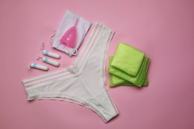 Photo of Flat lay composition with woman's panties and menstrual hygiene products on pink background