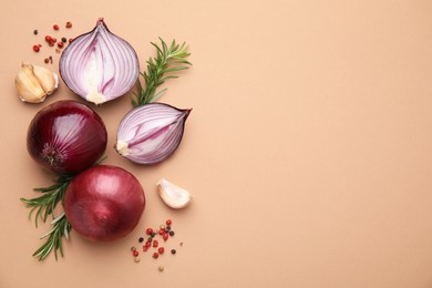 Fresh red onions, garlic, rosemary and spices on beige background, flat lay. Space for text