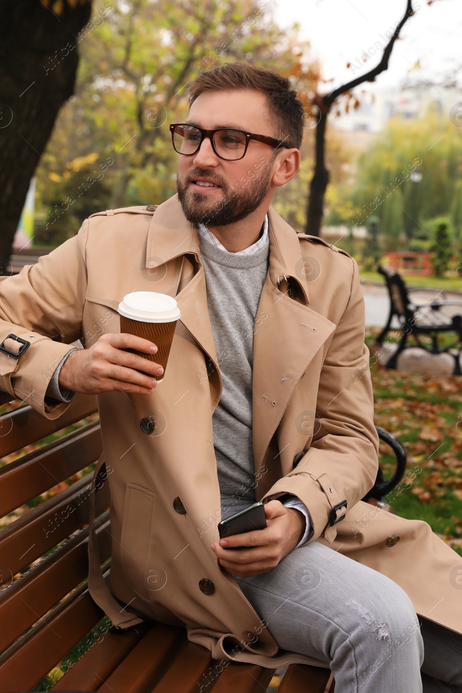 Photo of Handsome man wearing stylish clothes with cup of coffee in autumn park