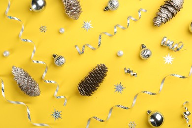 Flat lay composition with serpentine streamers and Christmas decor on yellow background