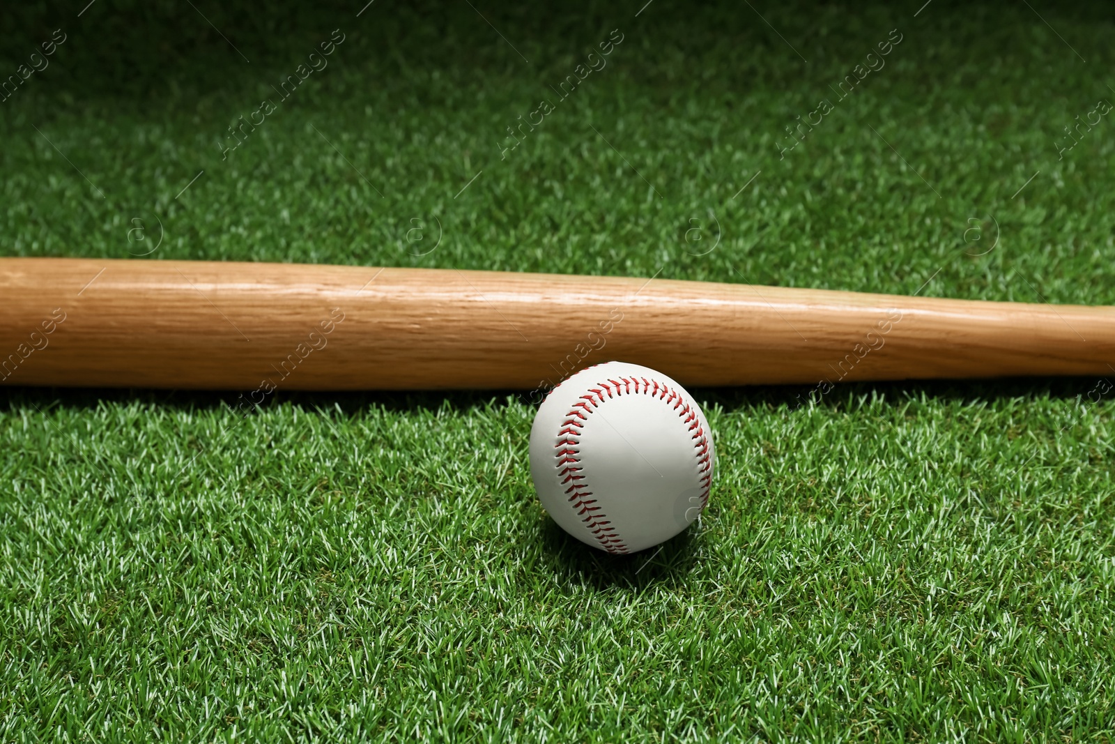 Photo of Wooden baseball bat and ball on green grass. Sports equipment