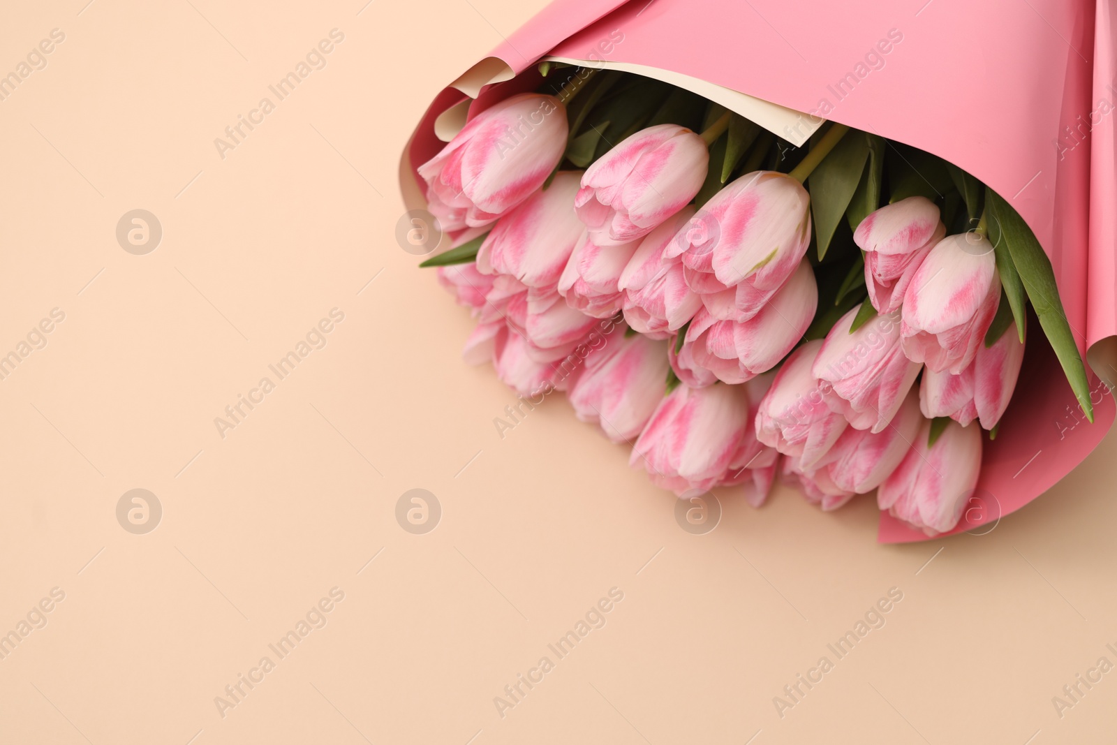 Photo of Beautiful bouquet of fresh pink tulips on beige background. Space for text