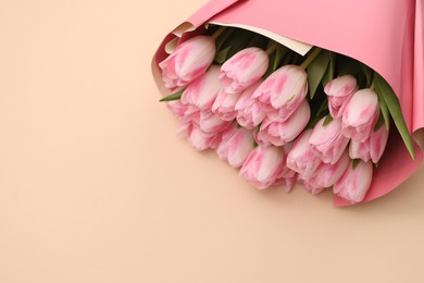 Photo of Beautiful bouquet of fresh pink tulips on beige background. Space for text