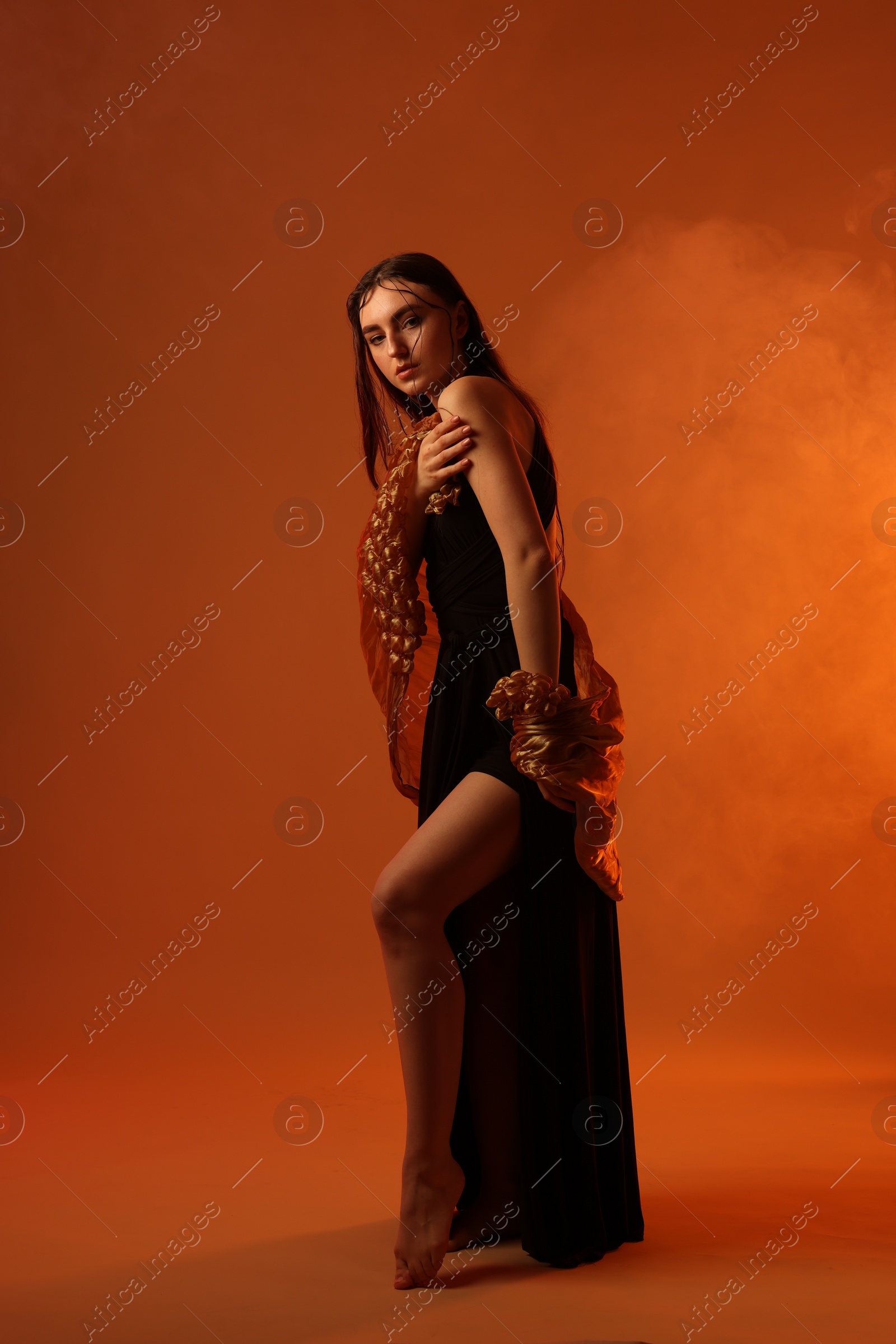 Photo of Beautiful woman in black dress and shawl posing on brown background